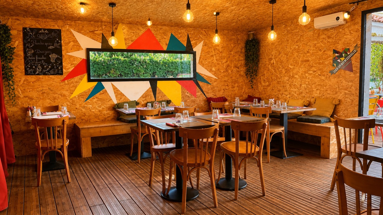 Salle chaleureuse du restaurant Au P'tit Chênex à Chênex, tables dressées, lumière douce et décoration bois